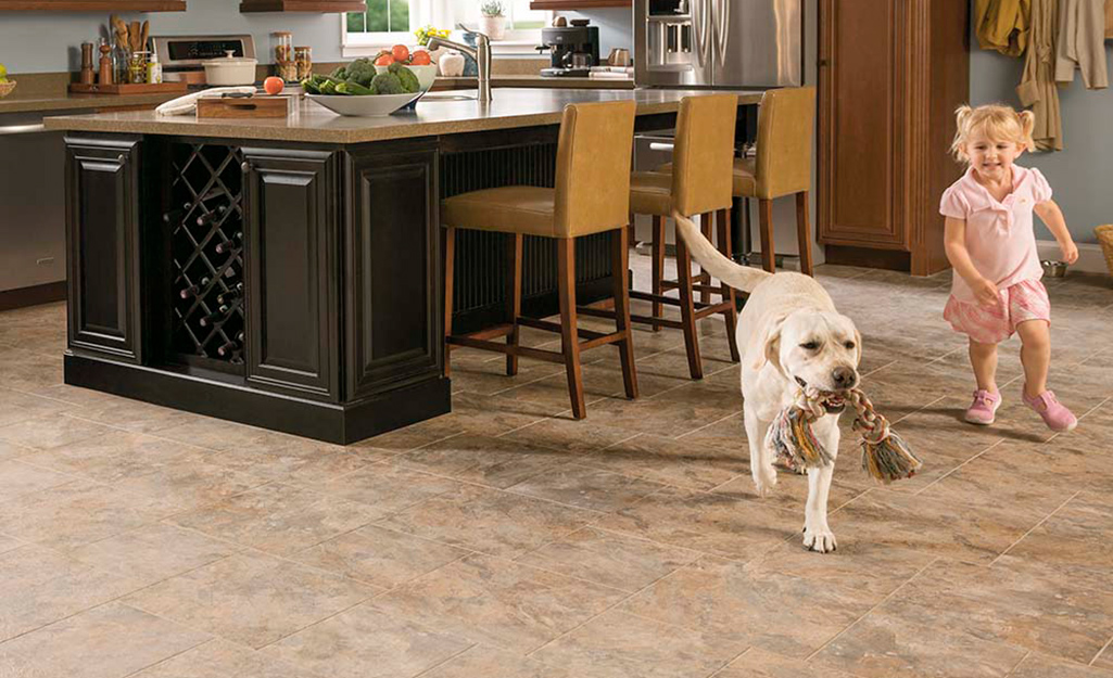 A dog and a child in a kitchen with tile flooring.