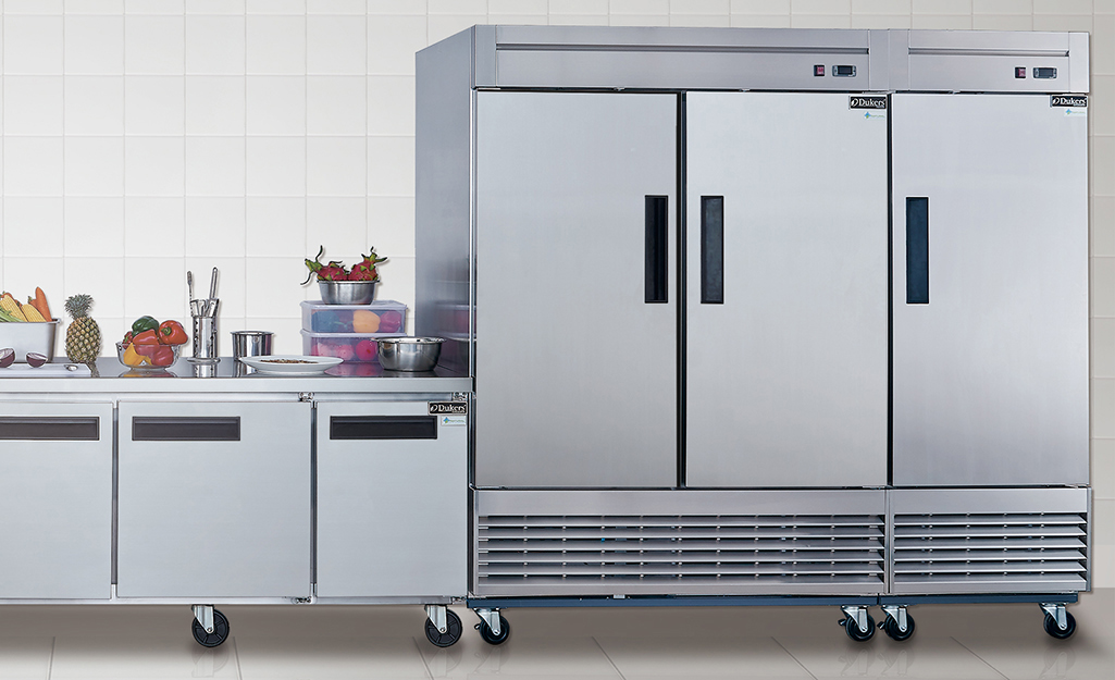 A row of single-door and multiple-door commercial freezers on wheels sit side-by-side.