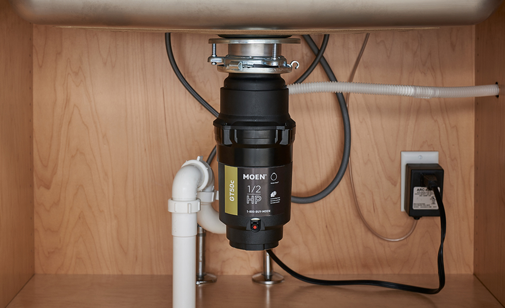 A continuous feed garbage disposal installed under a kitchen sink.