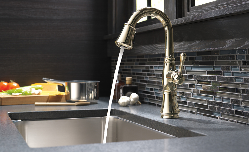 Water from a kitchen faucet running into a sink where a garbage disposal is installed.