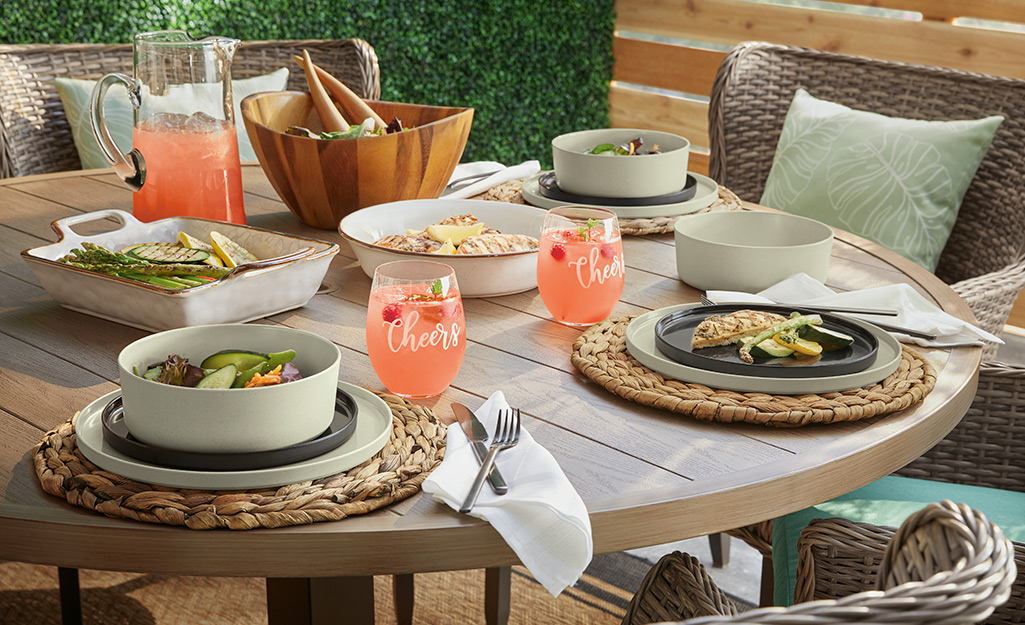 A patio table with place mats, dishes and glassware.