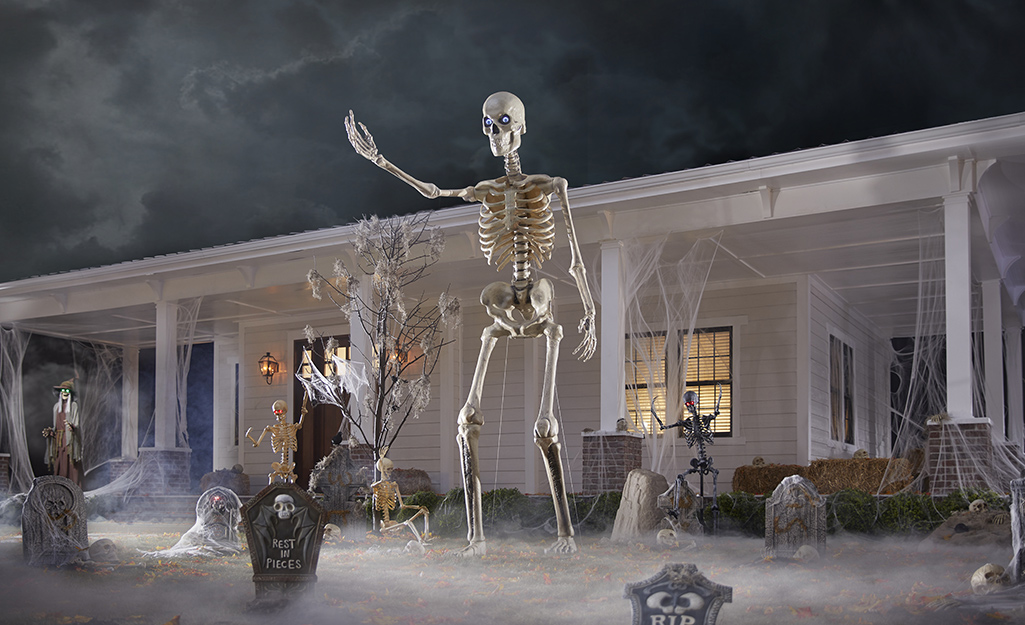 A 12-foot skeleton waves as it towers over a house.