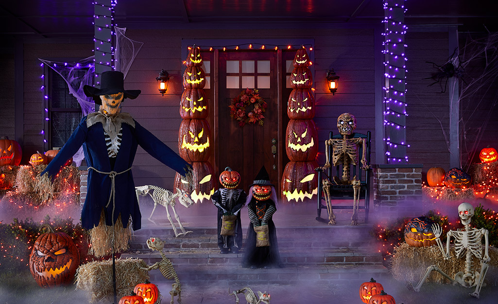 Grimacing LED Jack-o'-lanterns and creepy Scarecrow placed at the entrance of a home.