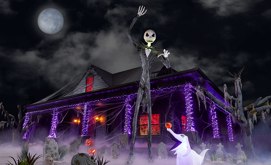 A 12-foot Jack Skellington towers over a house in a yard decorated for Halloween.