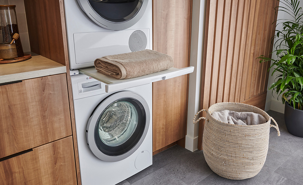 A stacked high-efficiency washer and dryer fit among wooden cabinets.