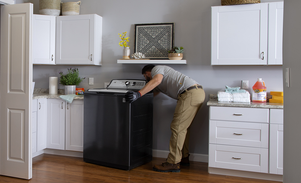 A man installs a high-efficiency washer in a laundry room.