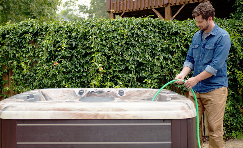 Someone filling a hot tub with water from a hose.