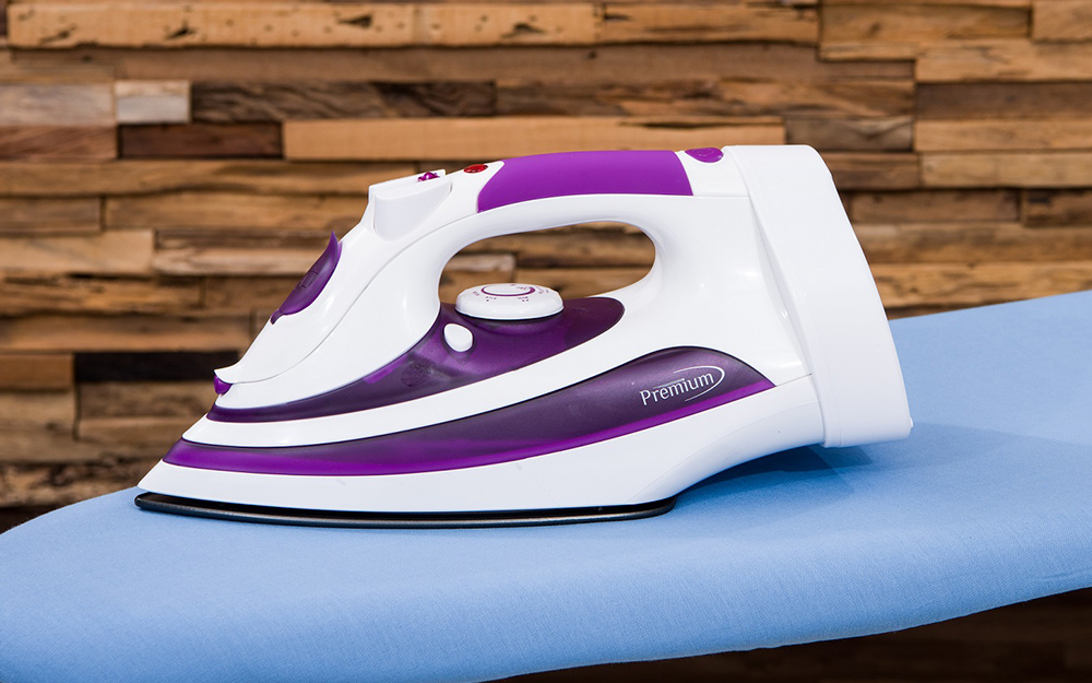 A purple and white iron on an ironing board.