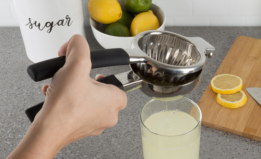 A person squeezes a lemon in a citrus juicer.