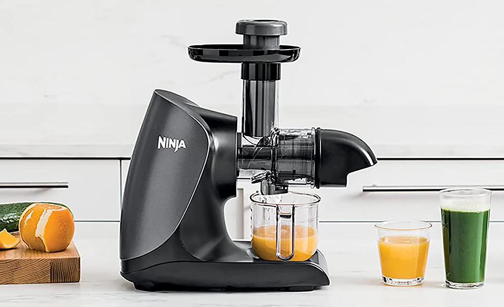 A countertop juicer and glasses of juice.