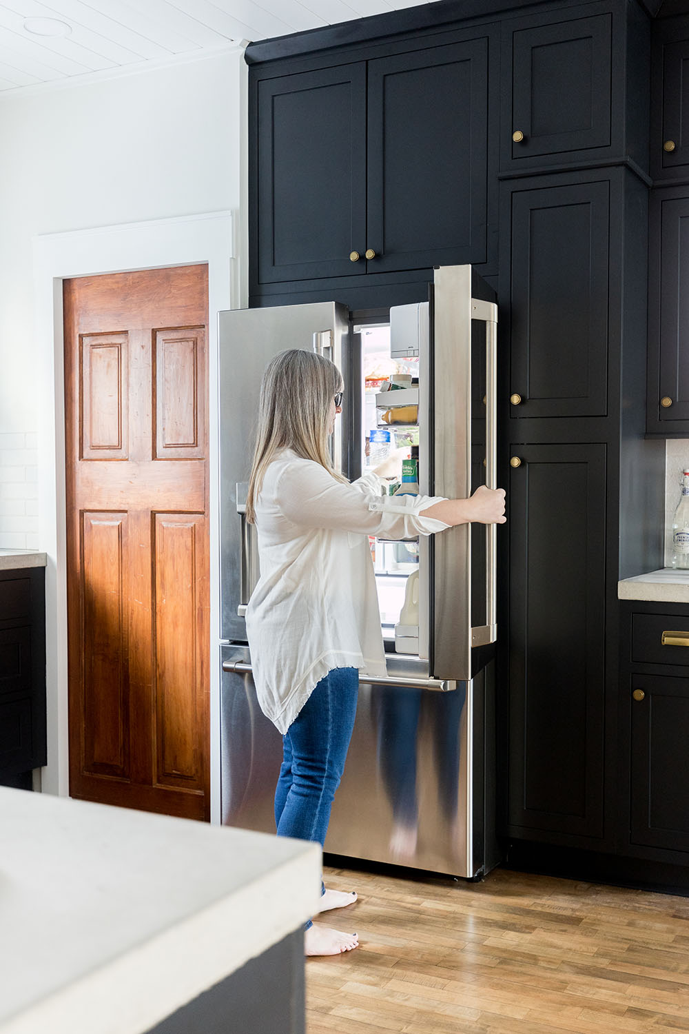 A woman reaches inside a GE Cafe refrigerator.