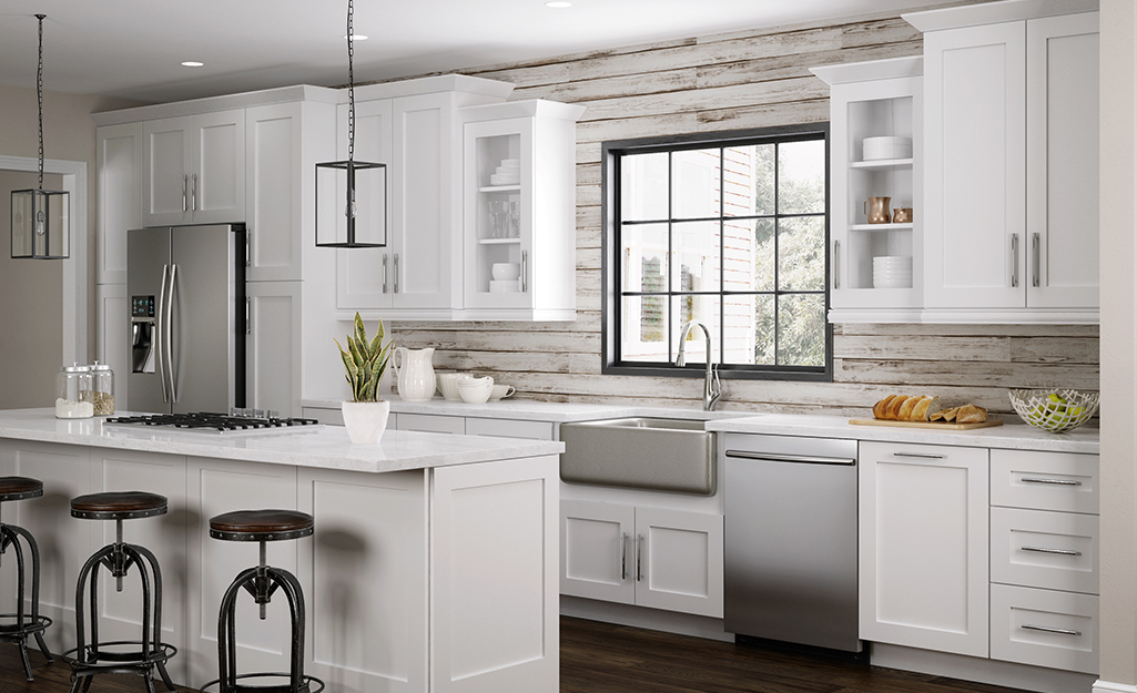 A kitchen featuring shiplap and white framed cabinets.