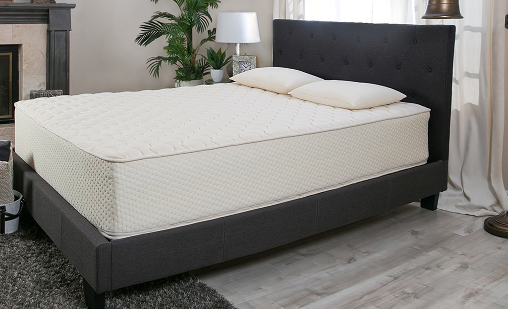 A bedroom with a latex mattress on a fabric bedframe.