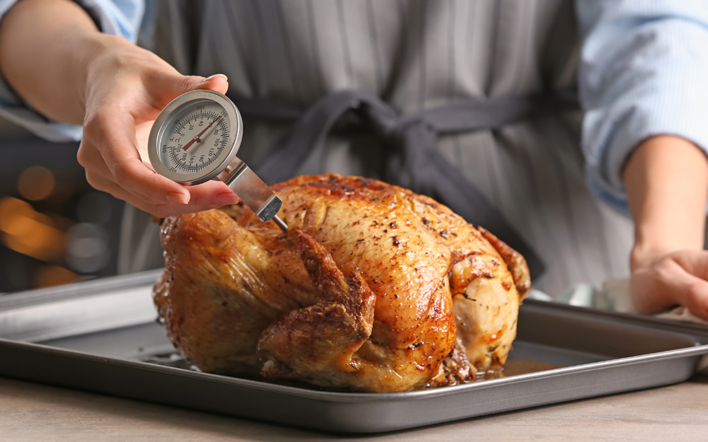 A dial thermometer measures the internal temperature of poultry.