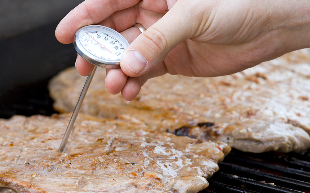 A dial cooking thermometer measures the temperature of meat.
