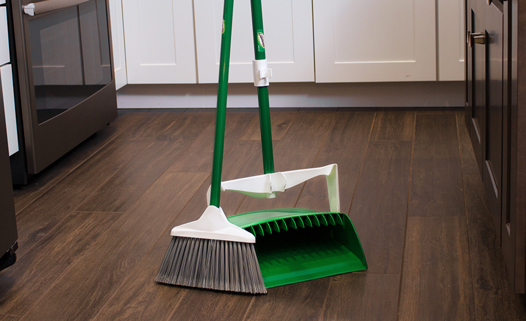 A broom and a dustpan in the kitchen.