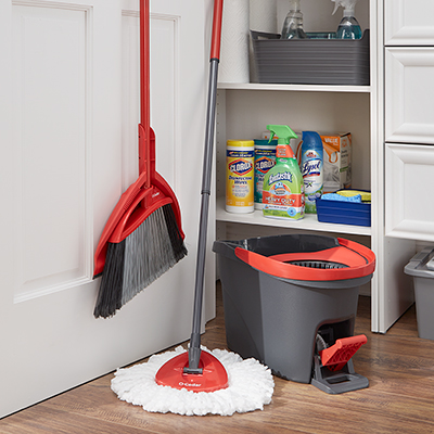 A mop and broom with an open closet.