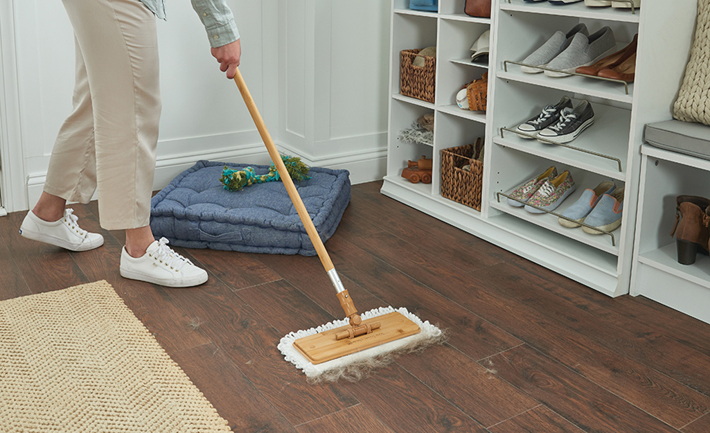 A person using a dust mop to gather pet hair.