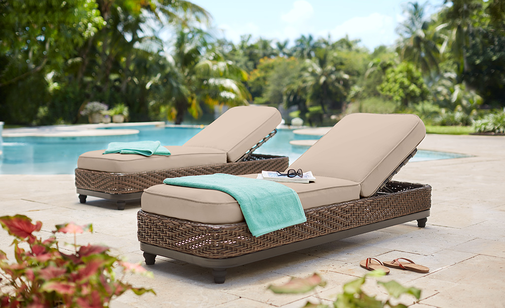 Two chaise lounges by a poolside.