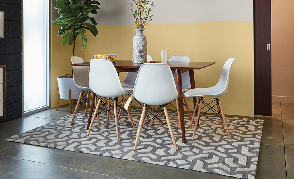 Dining chairs, table and an area rug laying on a stained concrete floor.