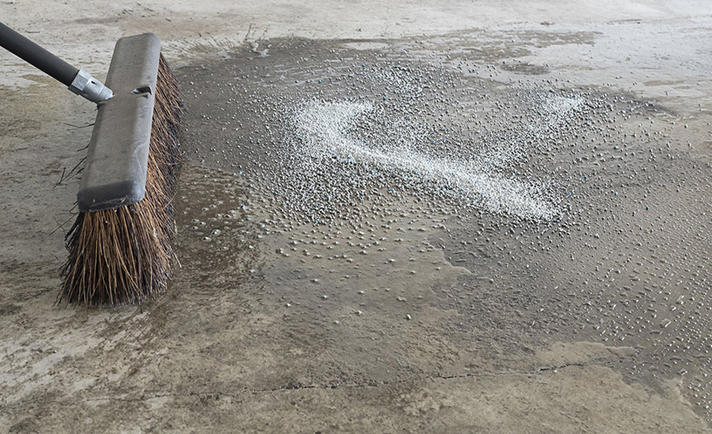 A person sweeps a concrete floor with a push broom.