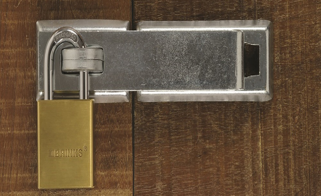 A hasp with a padlock on a wood surface.