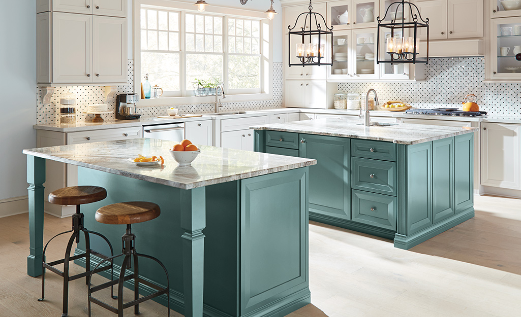 A kitchen with white upper cabinets and green lower cabinets.