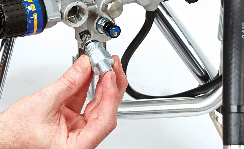 A person adjusting hardware on a paint sprayer.