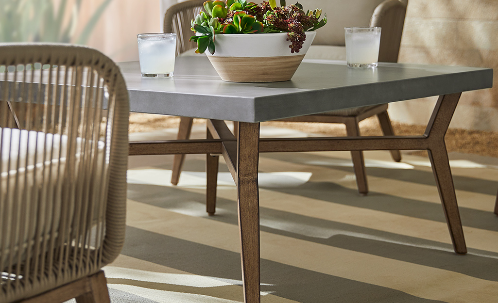 A coffee table with a gray top and wooden legs on a patio.