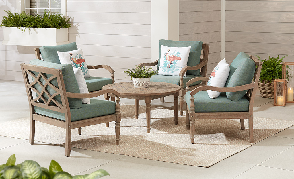 A bronze patio set with cushion chairs and a round table on a patio.