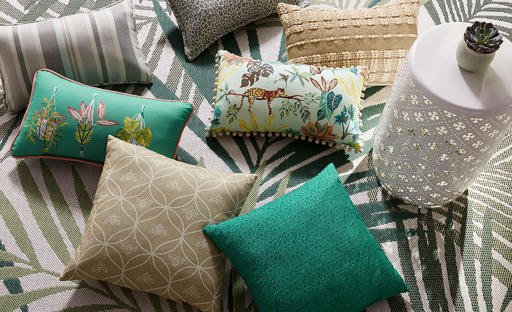 Pillows and other patio accessories on a green and white rug.