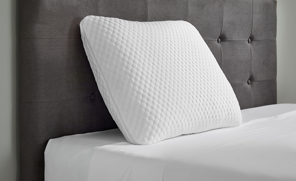 A memory foam pillow placed against a headboard.