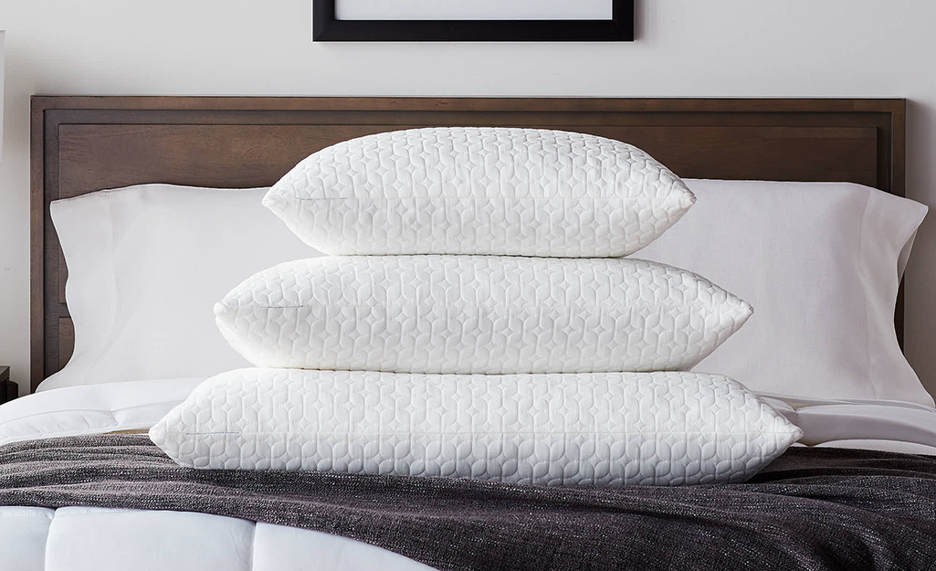 Different size bed pillows stacked on one another.