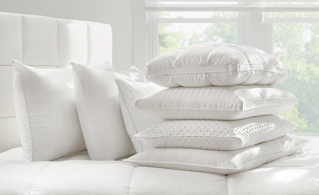 A variety of pillows on a bed.