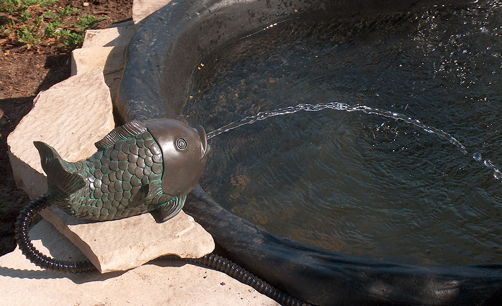 A fountain that looks like a fish disguises a pump that pushes water from the fish’s mouth into a garden pond. 