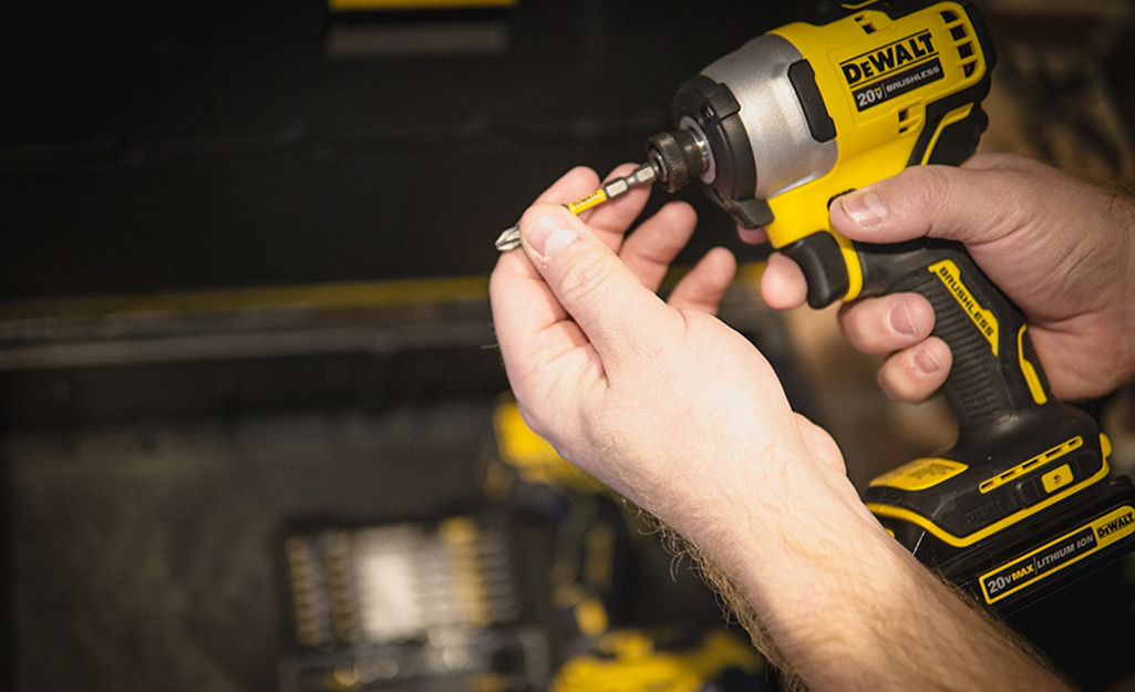 A person changing out the drill bit on a power drill.