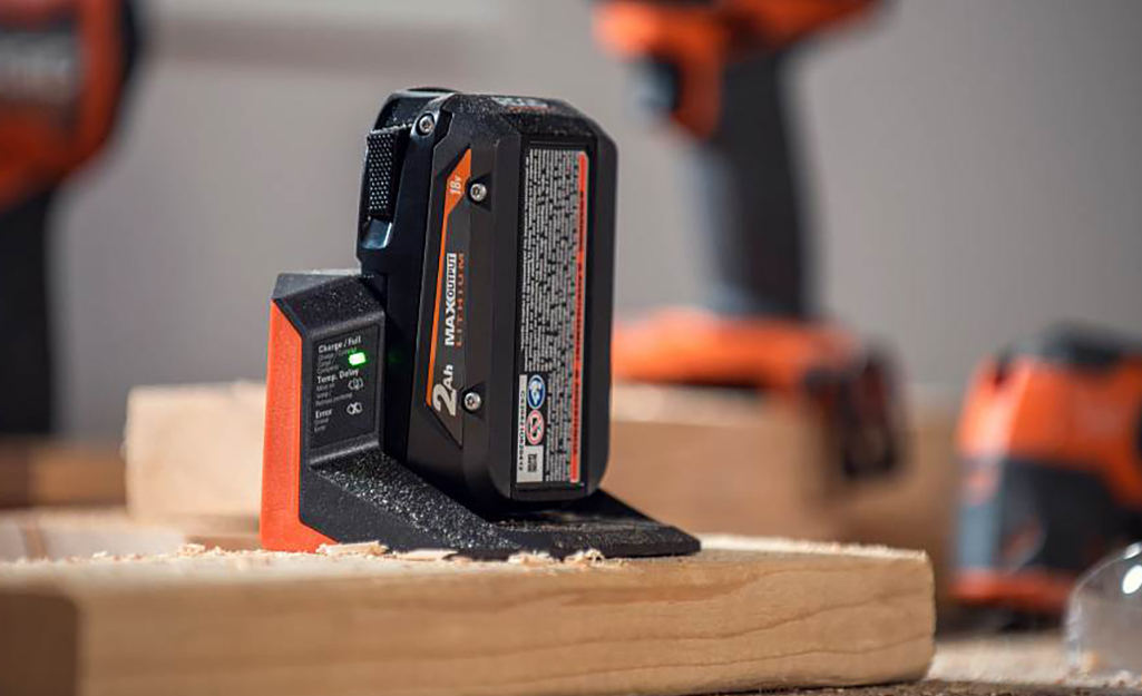 A power drill battery sitting on a wooden surface.