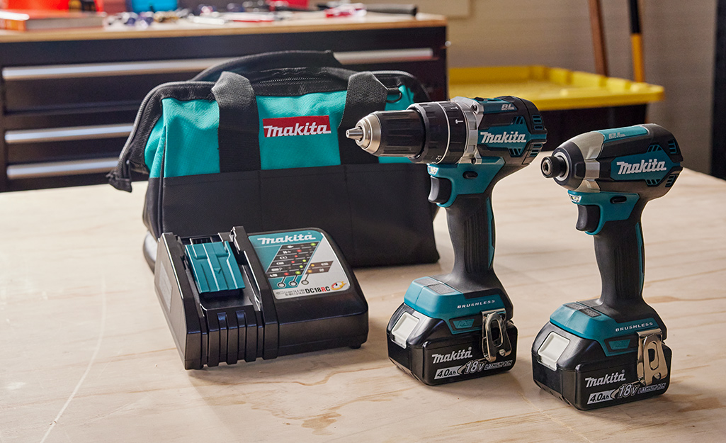 Two power drills side by side on a wooden table.