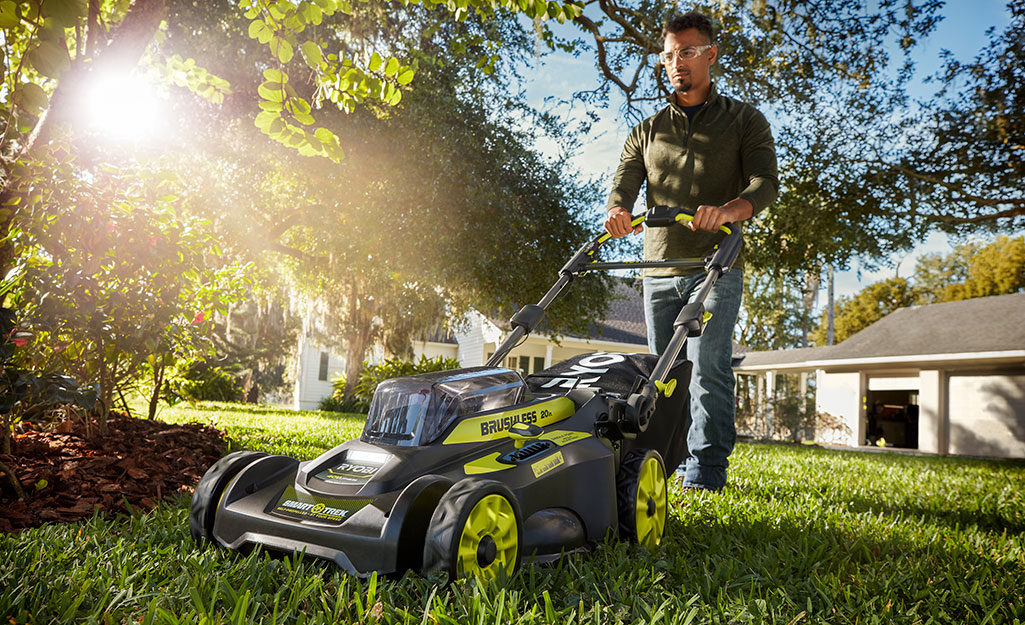 A man uses a push mower on large, healthy front lawn. A man uses a push mower on large, healthy front lawn.