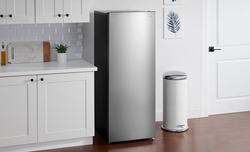 A low profile, free-standing refrigerator placed by a cabinet.