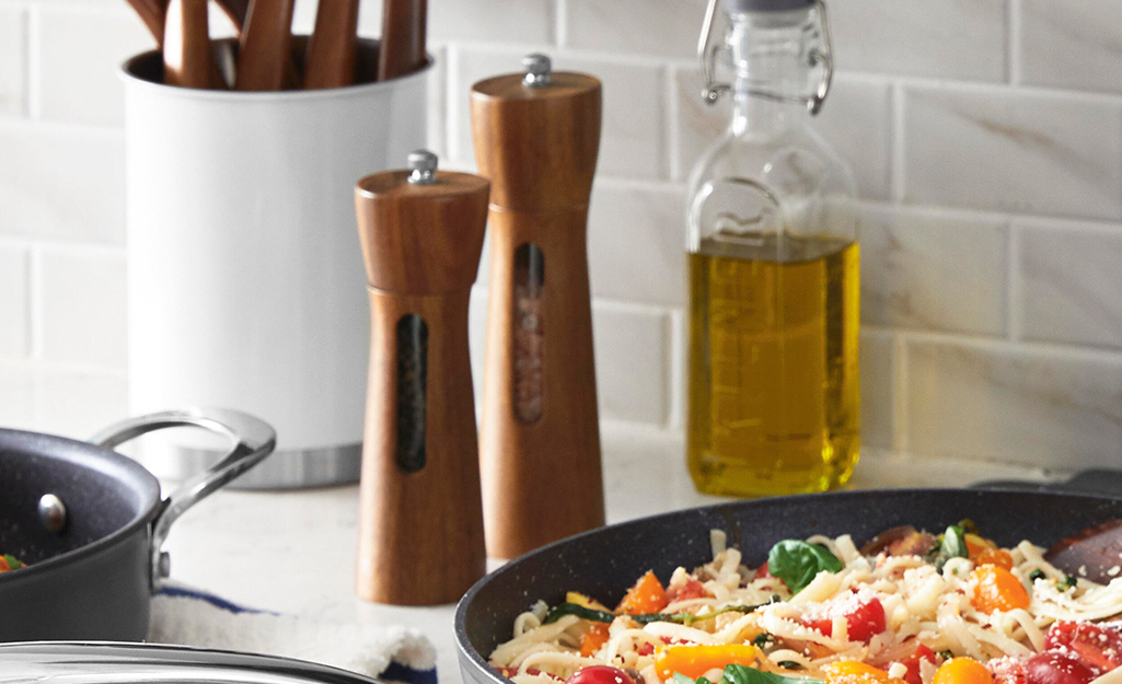 Mid-tier wooden salt and pepper mills with transparent chambers on a counter.