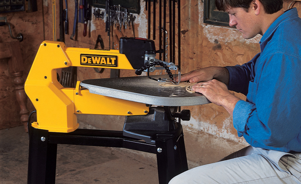 A person using a DeWalt scroll saw in a workshop.
