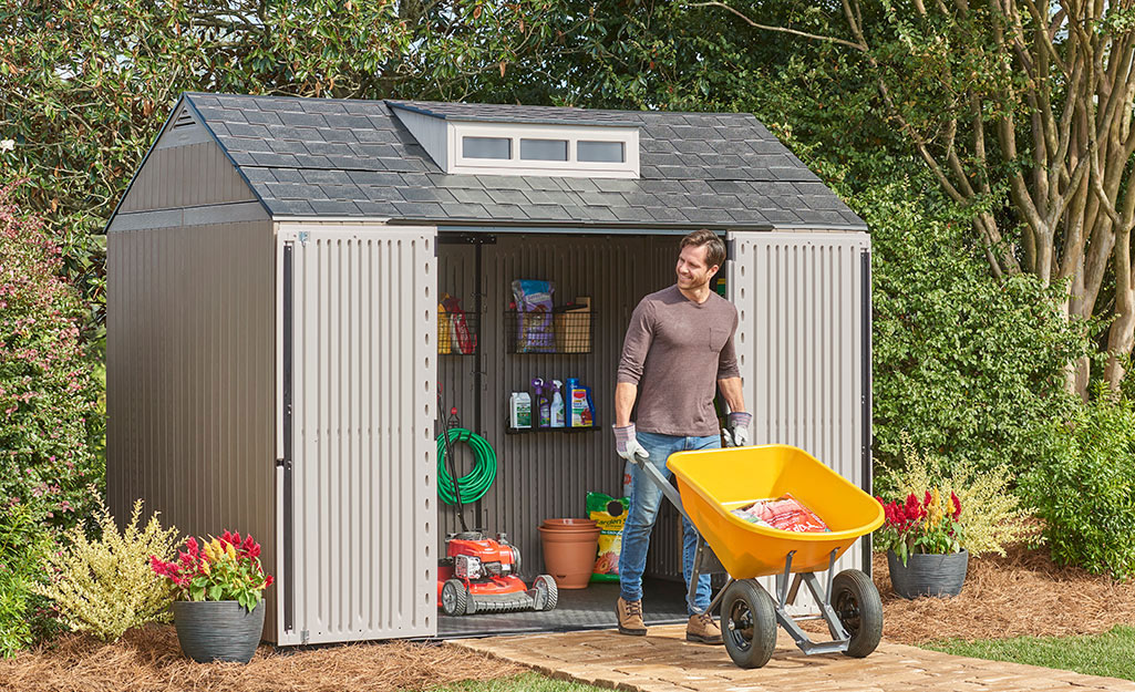 A metal shed with open doors revealing yard tools.