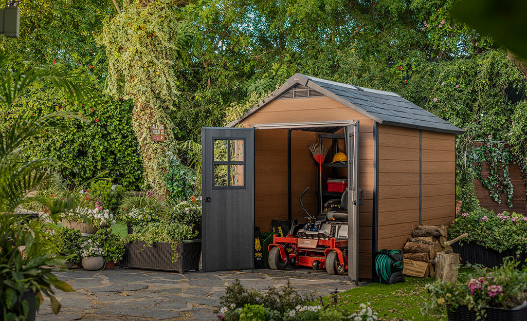 A garden shed with a lawn mower stored inside