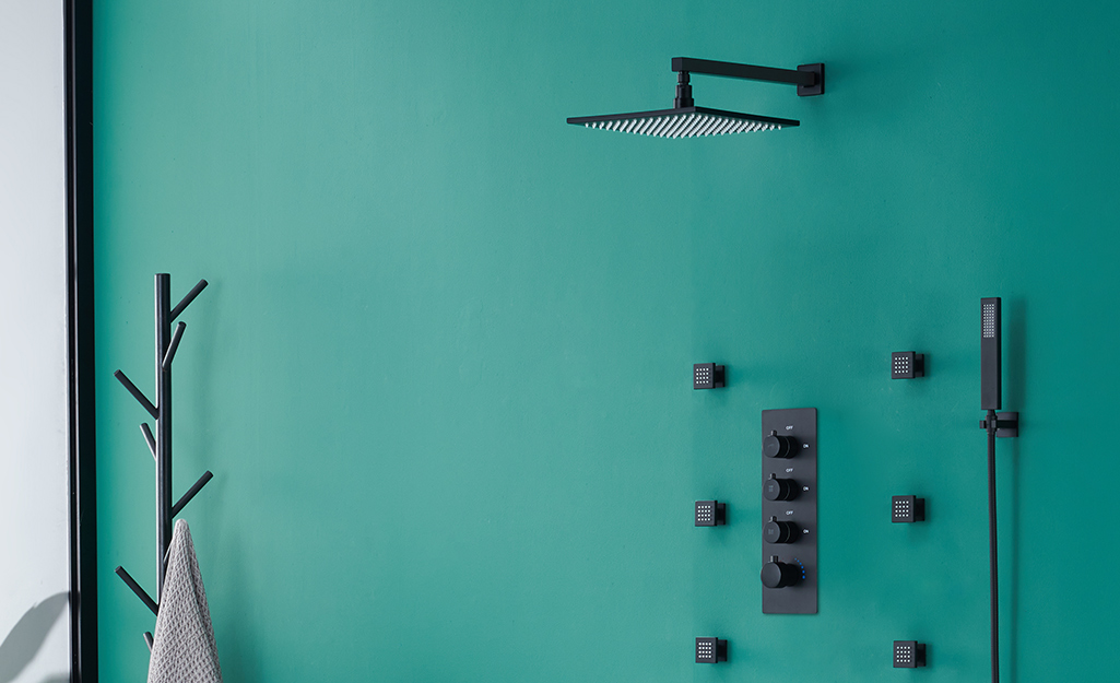 A black shower head with a rain spray pattern in a blue shower. 