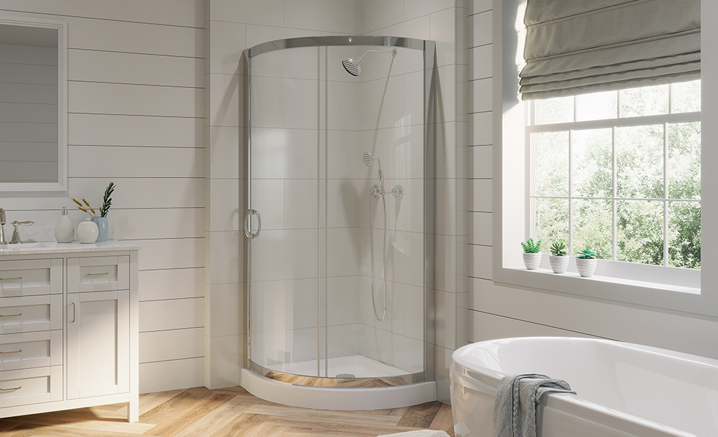 A corner shower with a rounded glass door enclosure.