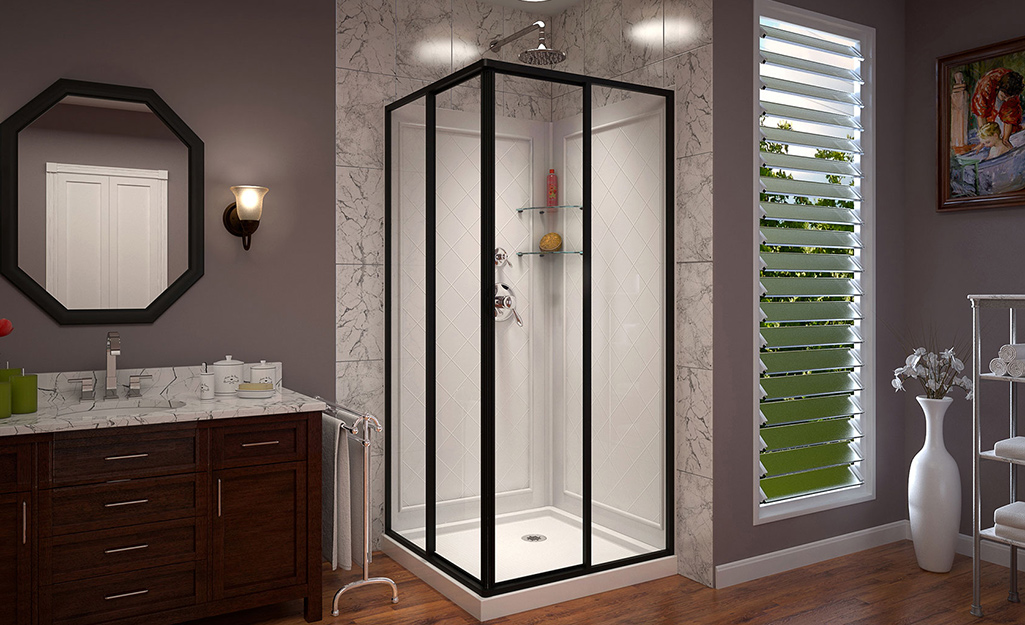 A framed glass corner shower with a drain in the back right corner.