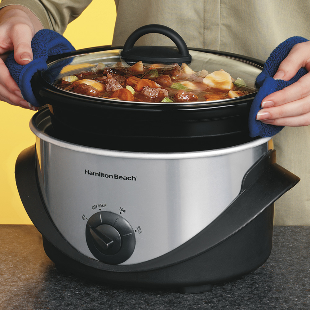 A person lifting the insert of a slow cooker.