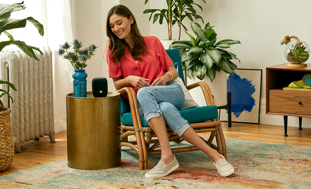 A person in a living room talks to a smart speaker.