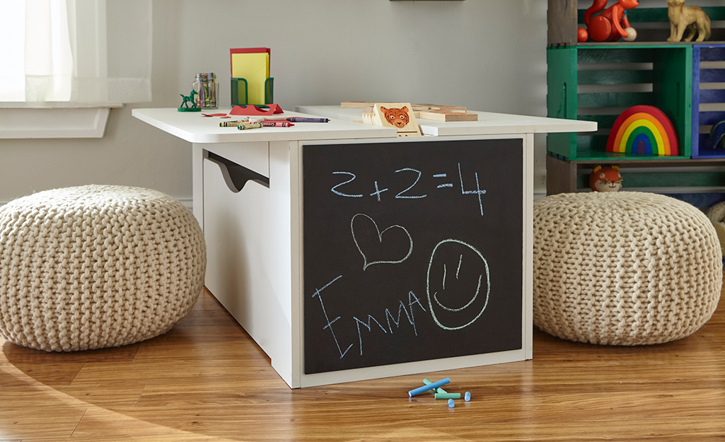 Chalkboard paint decorates one side of a child’s table in a playroom.